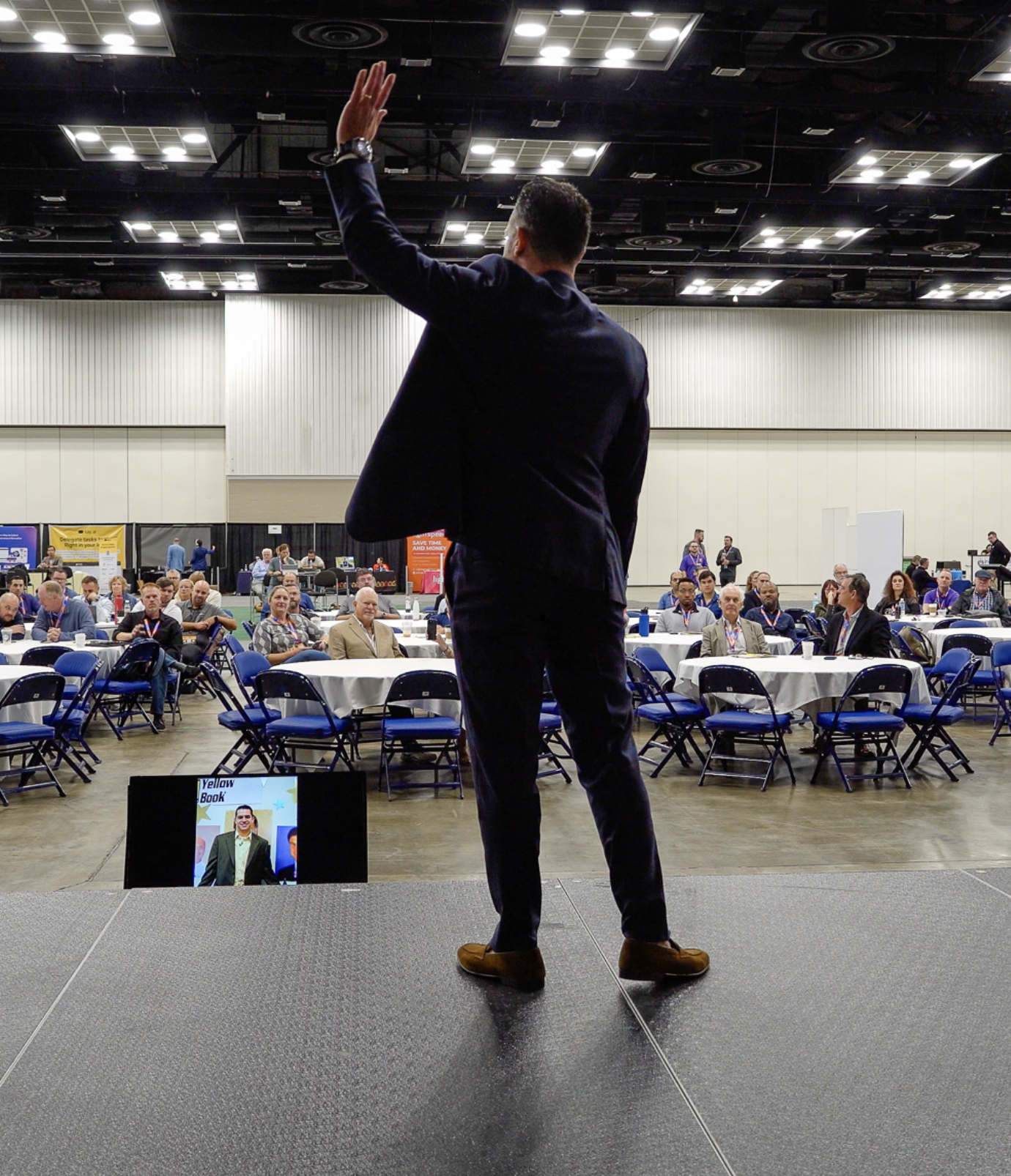 Michael standing on a stage looking at a crowd with a hand raised at IndieTech showcase in 2024